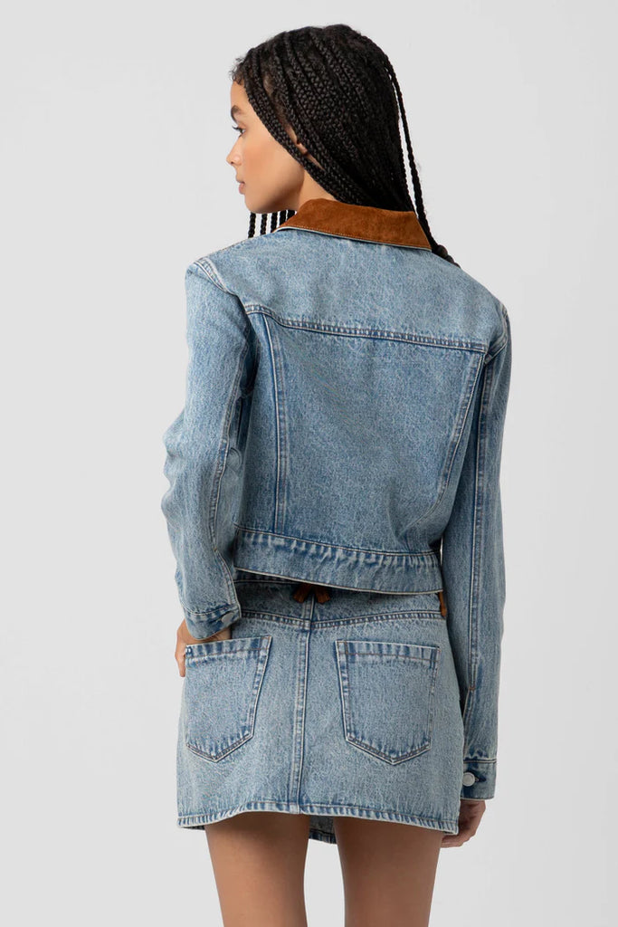 Person wearing a denim jacket and skirt set on a light gray background