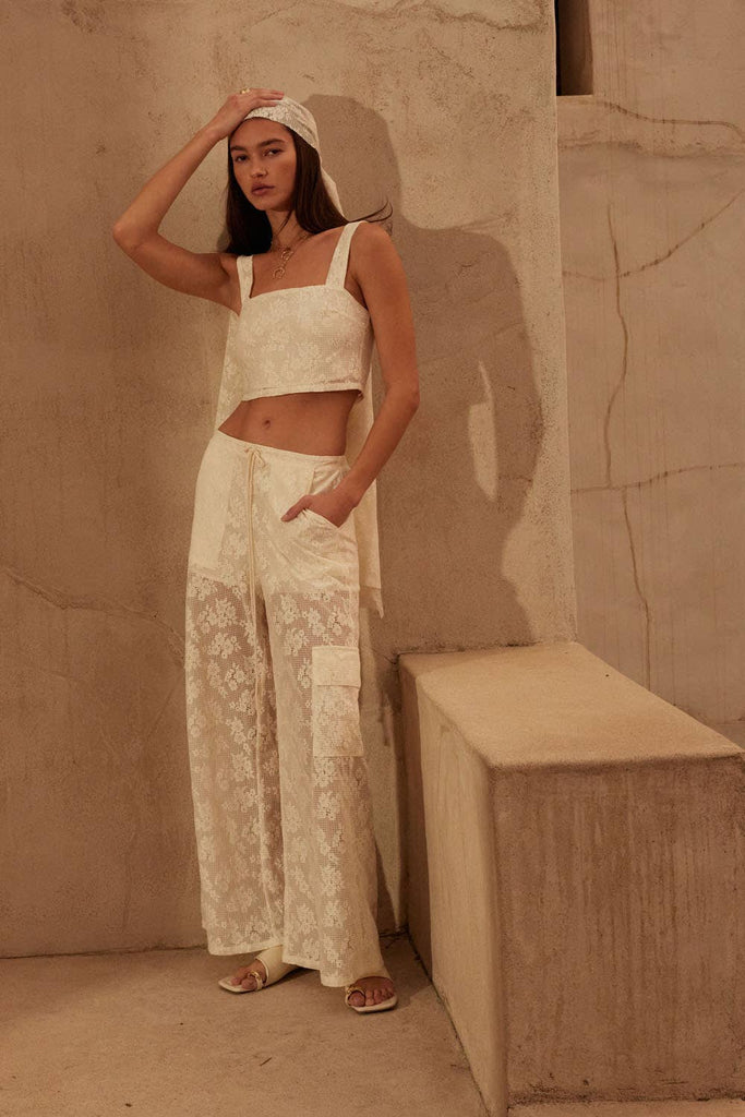 Model wearing ivory lace two-piece set with cropped top and drawstring wide-leg pants.