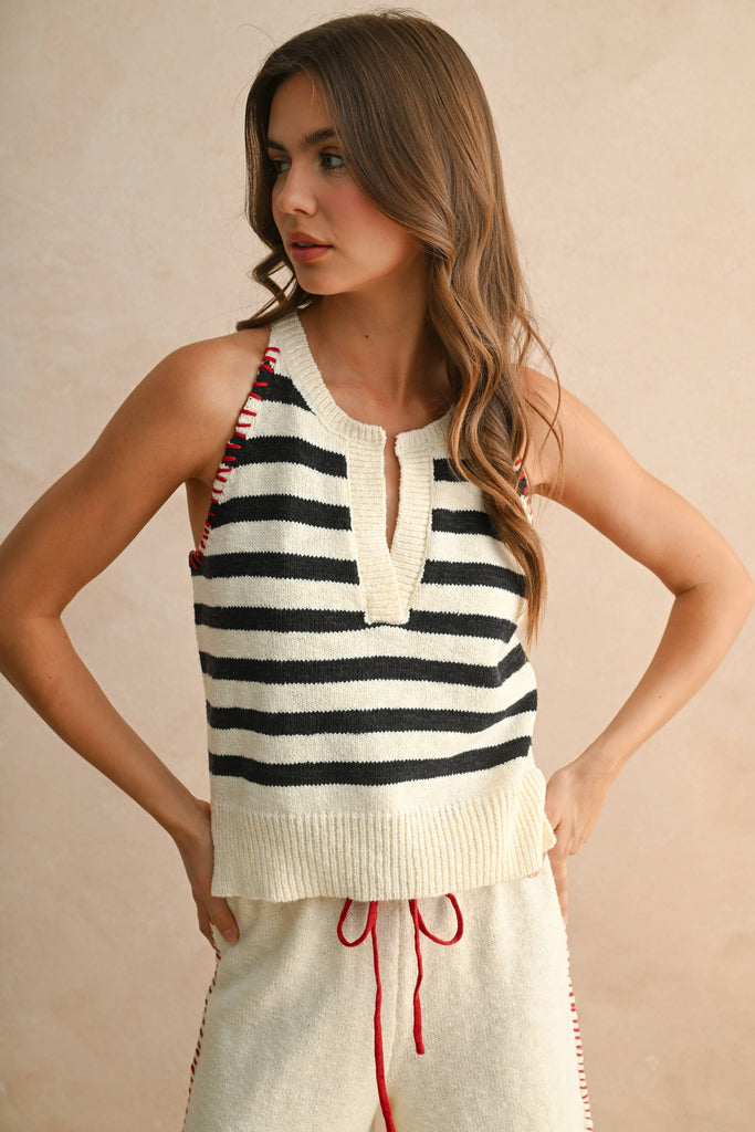 Woman wearing a cream knit set with striped sleeveless top and wide-leg pants with red drawstring.