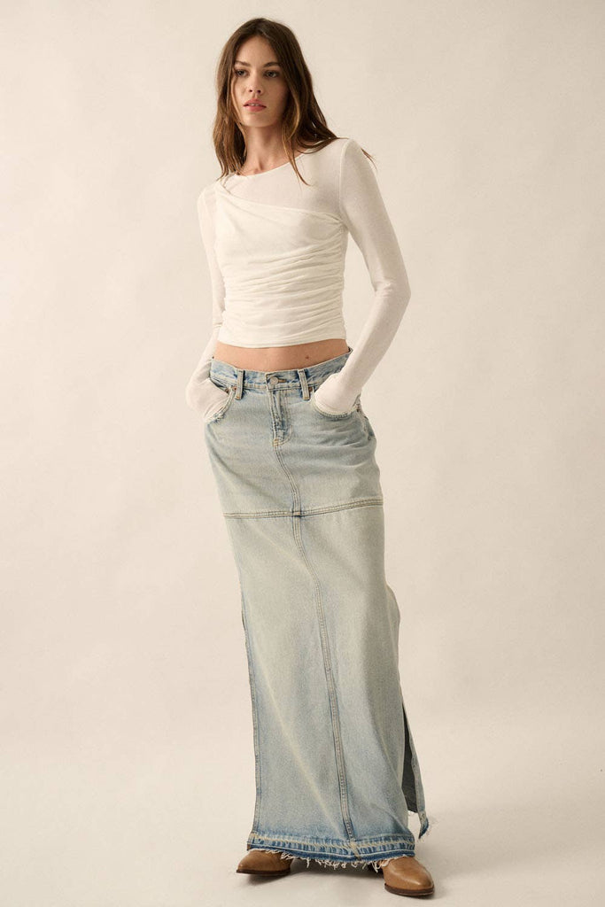 Woman wearing white long-sleeve draped top with asymmetrical ruching.