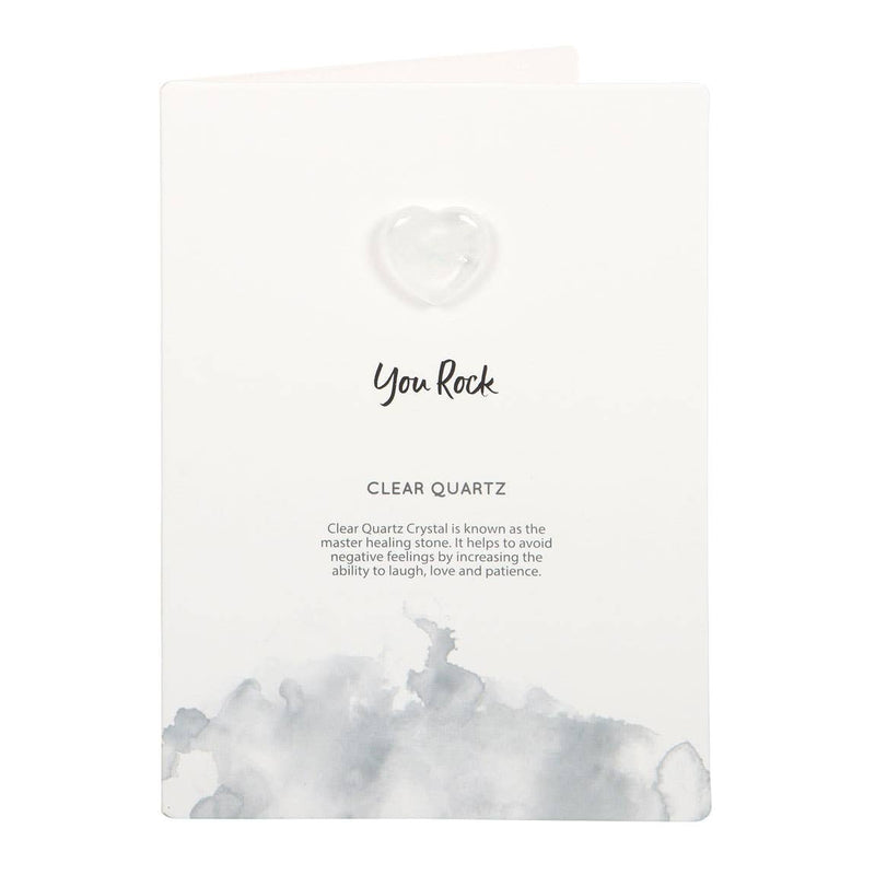 Hand holding a greeting card with a small clear quartz crystal heart and ‘You Rock’ text.