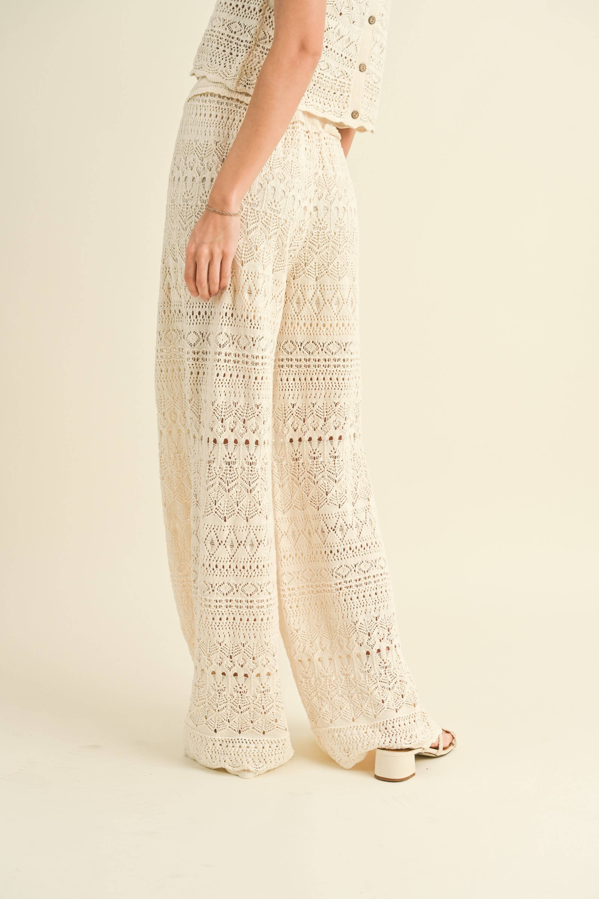 Model wearing cream-colored crochet wide-leg pants with intricate patterns and a high waist.