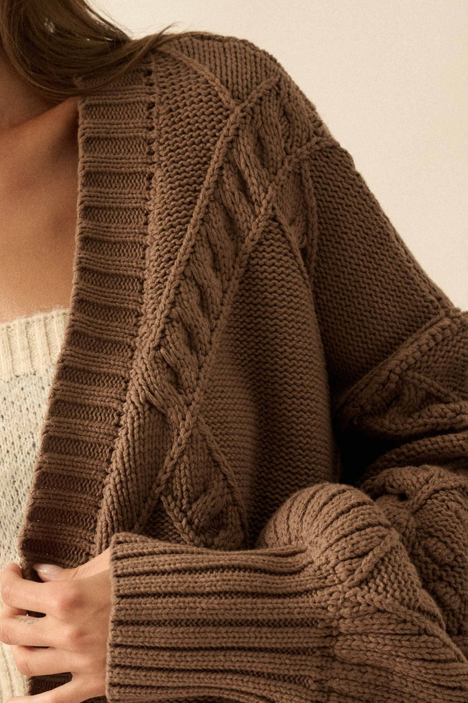 Brown knitted cardigan with intricate pattern on a neutral background