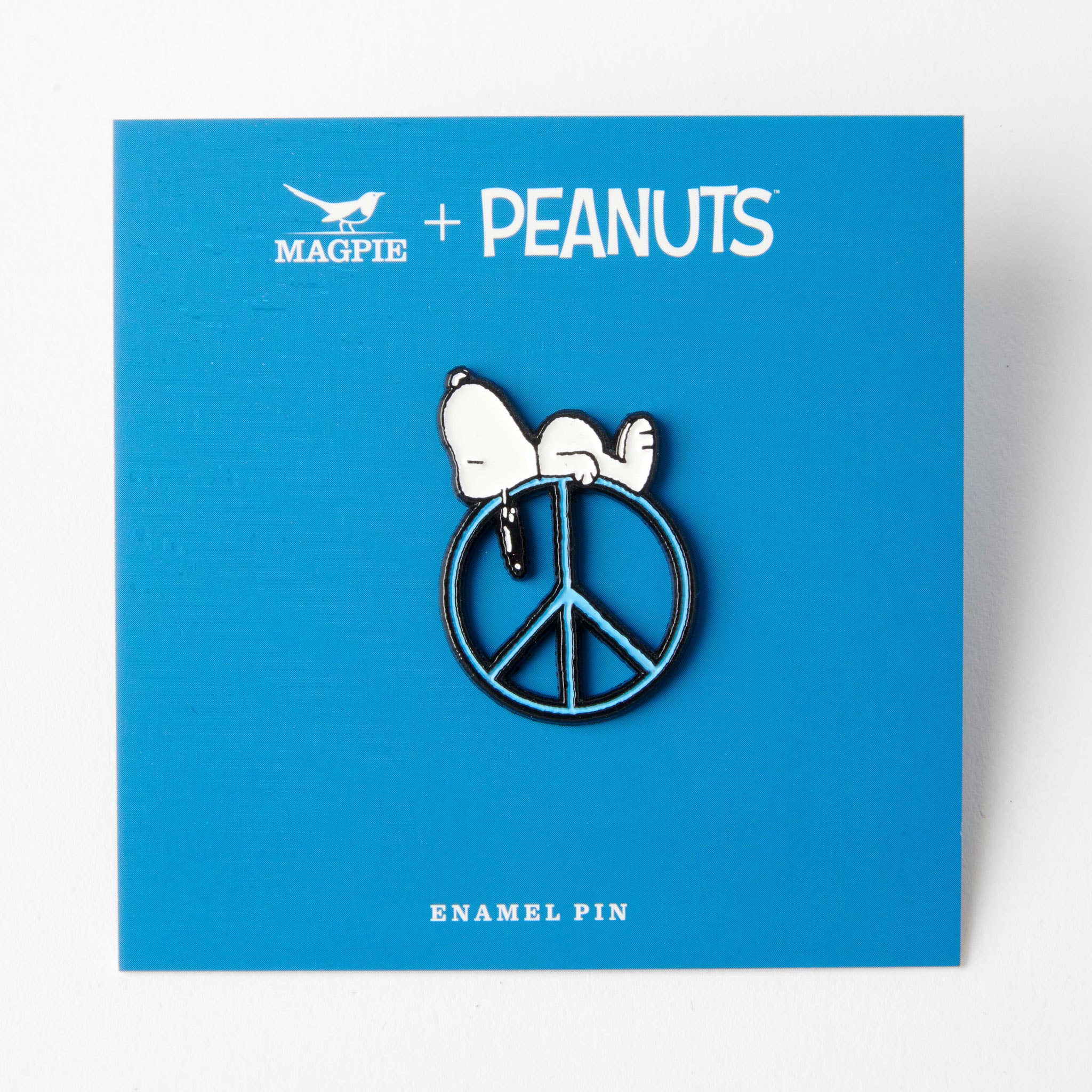 Snoopy enamel pin on a blue background labeled "Magpie + Peanuts," featuring a peace sign design.