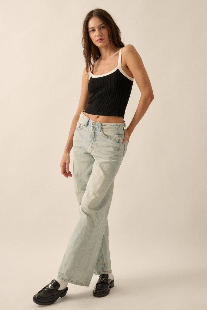 Black ribbed knit tank top with white trim on the straps and neckline, styled with light-wash denim jeans.