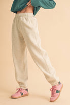 Woman wearing light heather beige fleece jogger pants with a relaxed fit and elastic waistband.