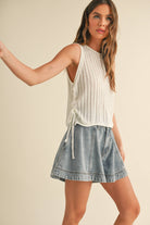 White open-knit tank top with side-tie details, styled with denim skort and jeans.