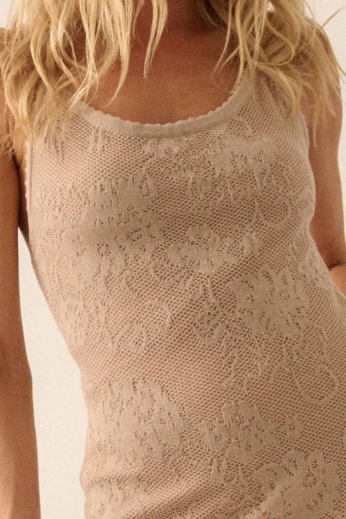 Woman wearing a sheer white lace maxi dress with spaghetti straps and floral detailing.