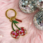 Disco Cherries Enamel Keychain featuring a pair of cherries with a sparkling, disco ball-inspired design on a pink background.