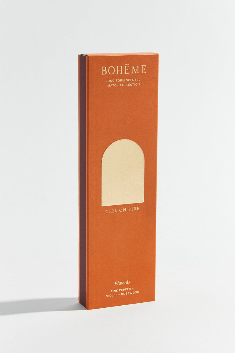 A box of Boheme Phoenix scented matches with a pink and orange design, indicating the scent as 'Girl on Fire' from the Long Form Scented Match Collection.