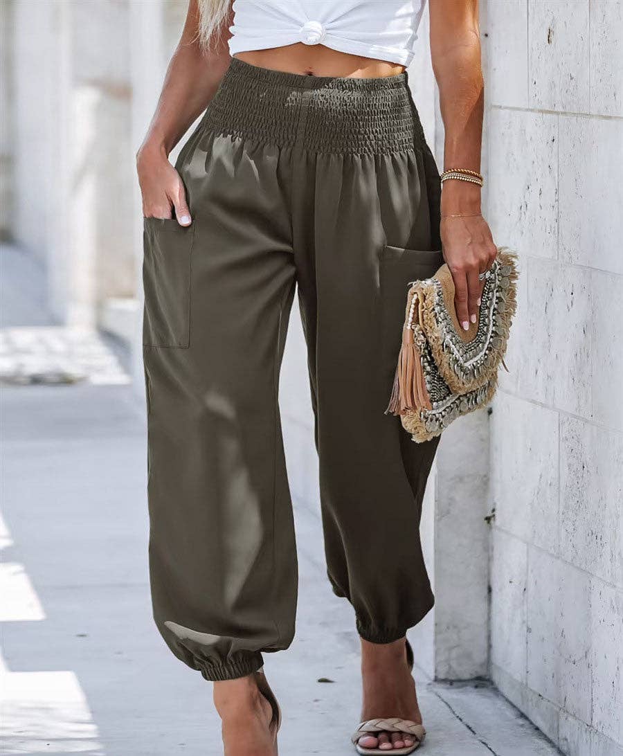 Woman wearing Serenity High-Waist Comfort Pants in beige and olive colors, paired with a white crop top and heels, carrying a decorative clutch.