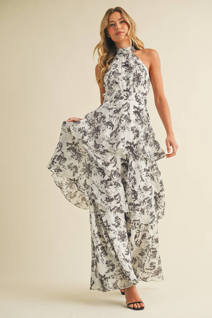 Woman wearing a halter neck tiered maxi dress with black floral print and ruffle layers