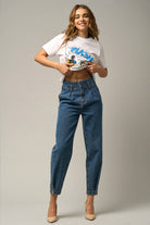  Model wearing high-waist balloon jeans with a relaxed silhouette and slightly tapered legs, paired with a casual graphic t-shirt and neutral heels.