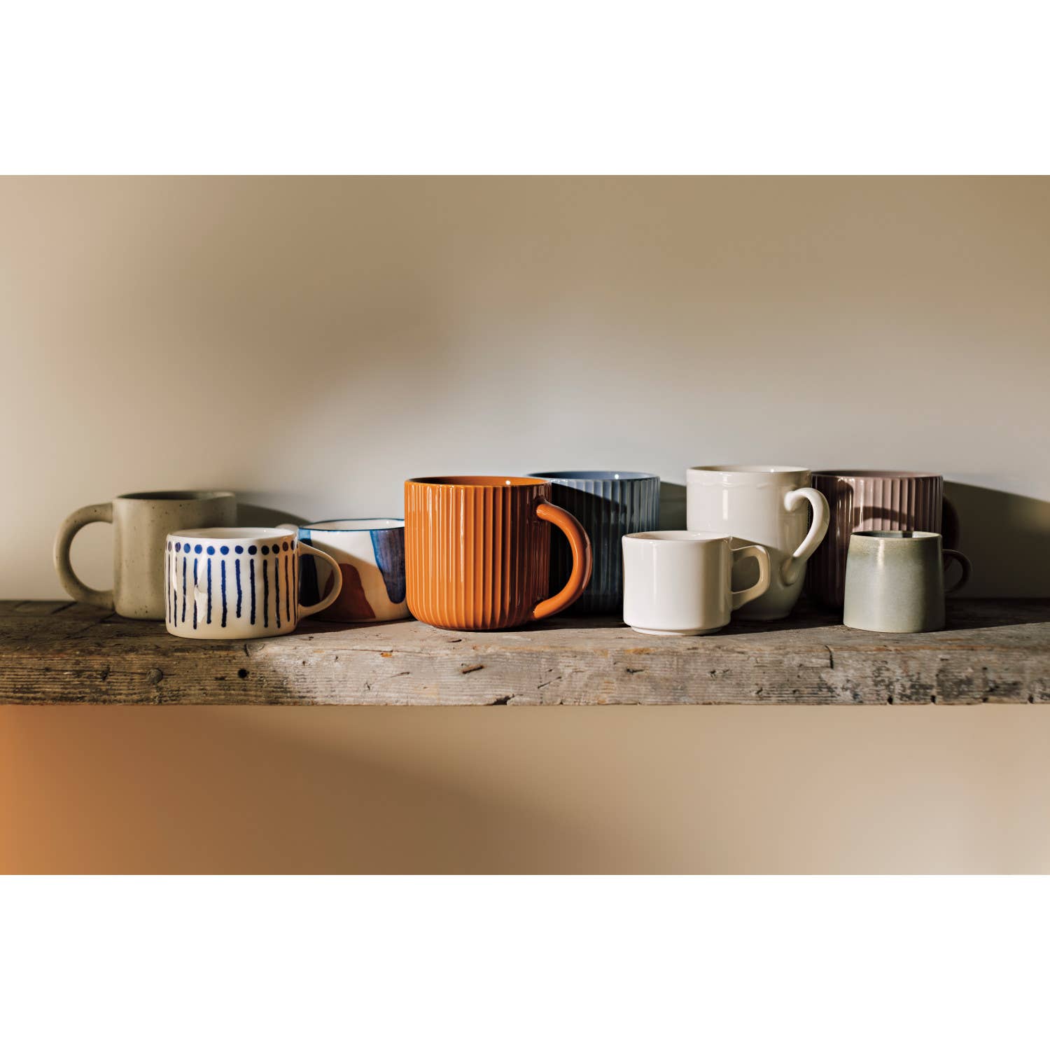 Collection of ceramic mugs on a wooden surface with a neutral background