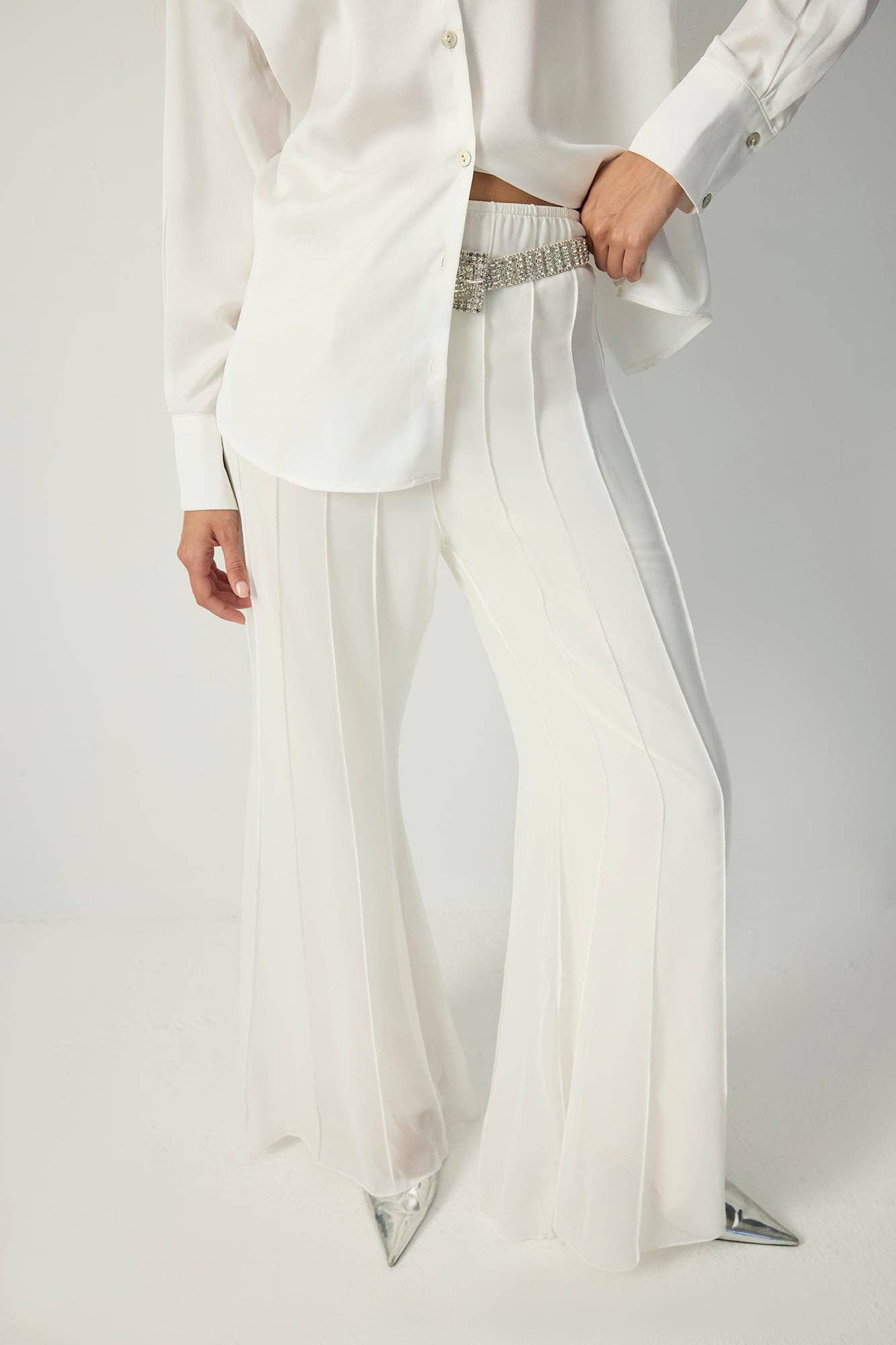 White pleated chiffon flared trousers with high waist and flowy wide legs.
