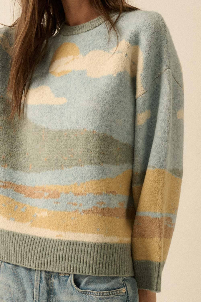 Sweater with a landscape design featuring blue, yellow, and green colors.