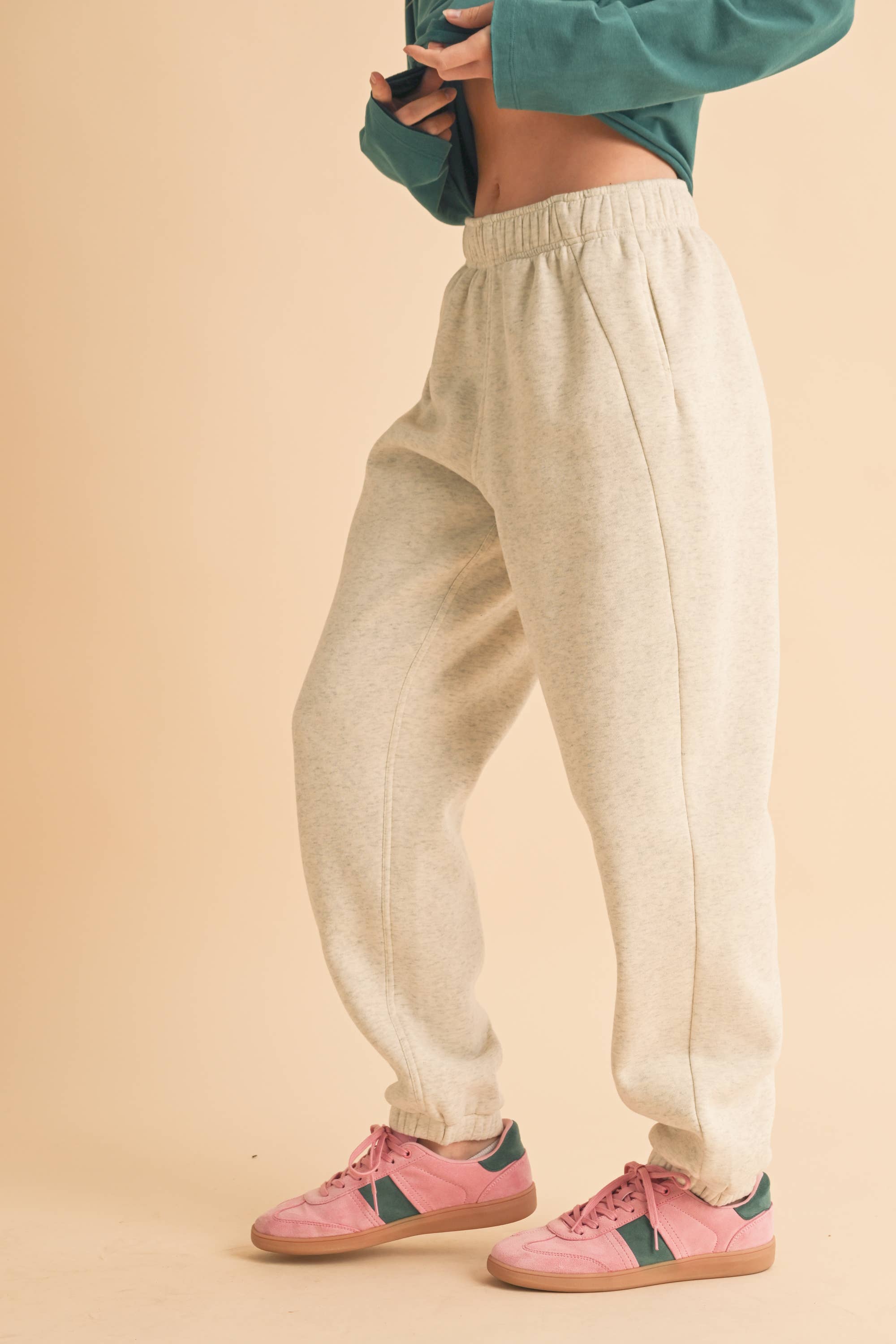 Woman wearing light heather beige fleece jogger pants with a relaxed fit and elastic waistband.