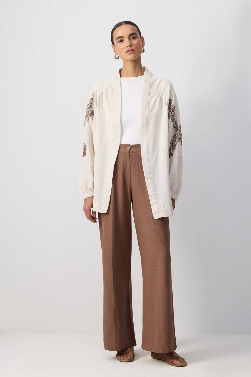 Back view of a woman wearing a cream embroidered kimono with sequin detailing and wide sleeves.