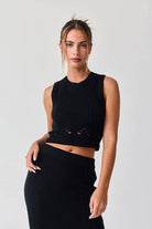 Woman wearing a black sleeveless crochet top and midi skirt set.