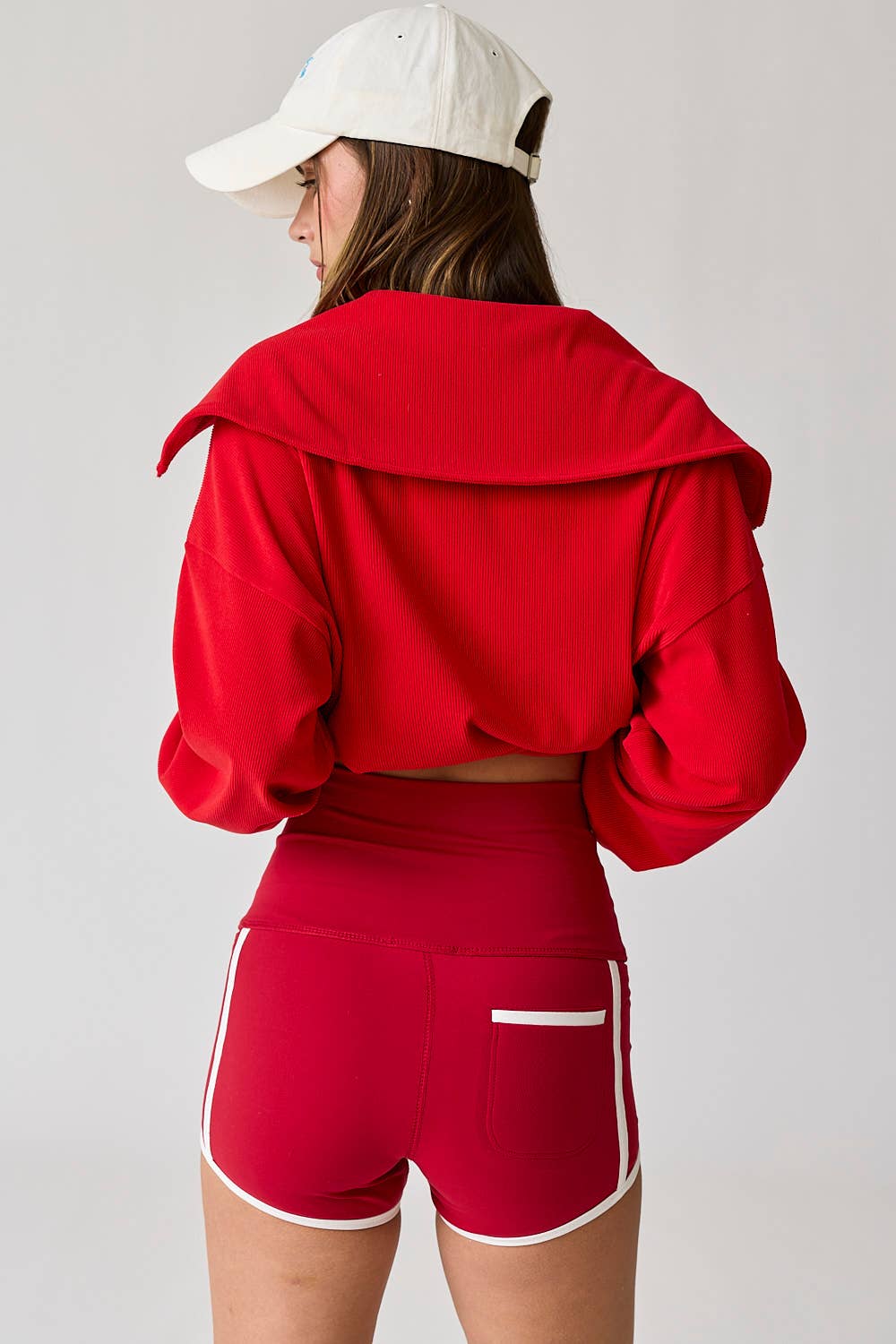 Woman wearing high-waist red shorts with white contrast piping. / Woman wearing high-waist green shorts with white contrast piping.