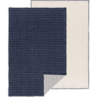 Two dishtowels, one with a midnight blue grid pattern on a light background and another with a solid light beige color, both laid out flat.