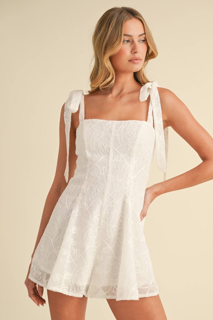 White embroidered romper with shoulder tie straps, worn by model facing front and back