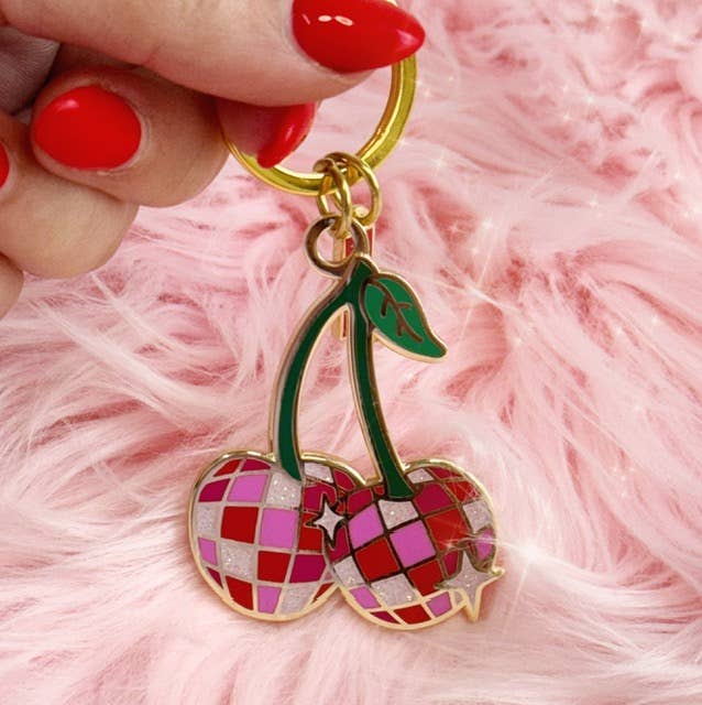 Disco Cherries Enamel Keychain featuring a pair of cherries with a sparkling, disco ball-inspired design on a pink background.