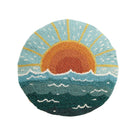 Round cushion with a hand-hooked sunrise over the ocean design in coastal colors.