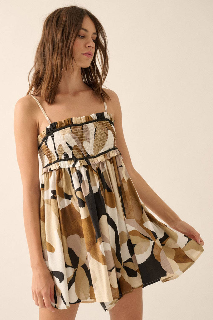 Woman wearing an abstract printed romper in warm earth tones with a smocked bodice and flowy shorts.