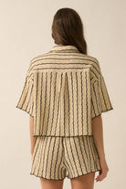 Woman wearing a beige striped two-piece lounge set with button-up shirt and matching drawstring shorts.