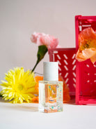 Maison Matine Bain de Midi perfume bottle styled with fresh flowers and a pink crate
