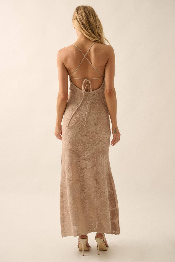 Woman wearing a sheer white lace maxi dress with spaghetti straps and floral detailing.