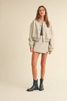 Model wearing a wool-blend jacket and mini skirt set in a neutral tone, styled with a striped tee and relaxed fit, showcasing casual elegance.
