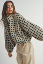 Woman wearing a beige and green checkered fleece jacket with a zip closure, paired with a white crop top and beige corduroy pants.