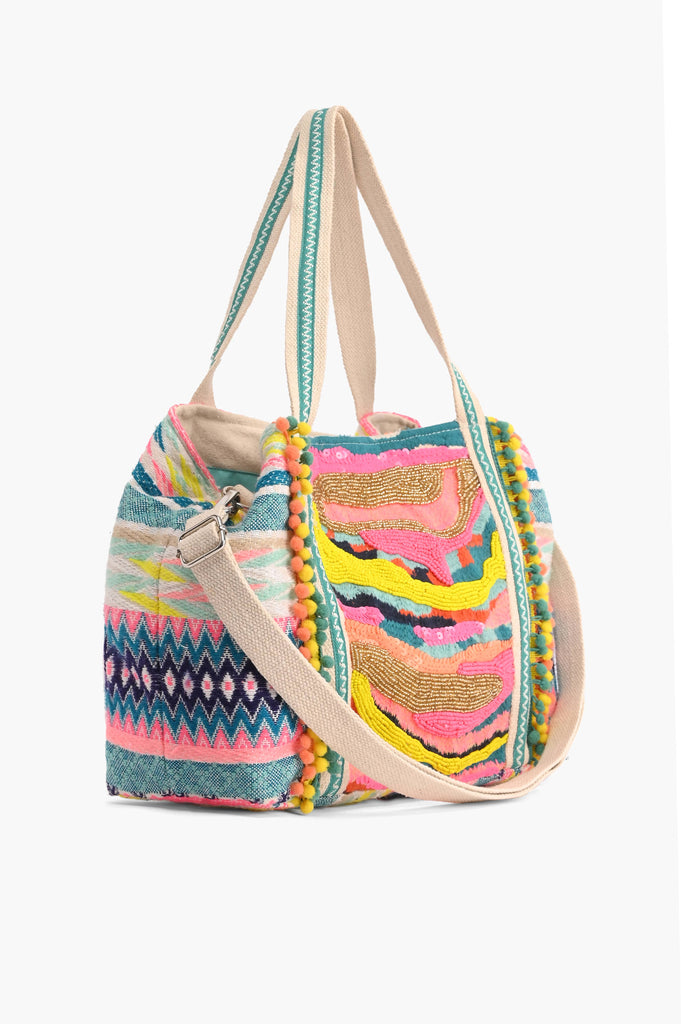 Multicolor embroidered crossbody bag with abstract beading, patterned sides, pom-pom trim, and detachable strap.