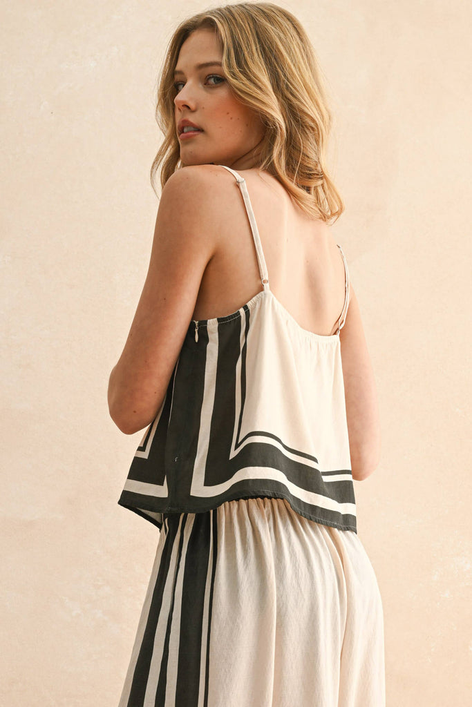 Woman wearing a cream and black striped two-piece set with a flowy top and wide-leg pants.