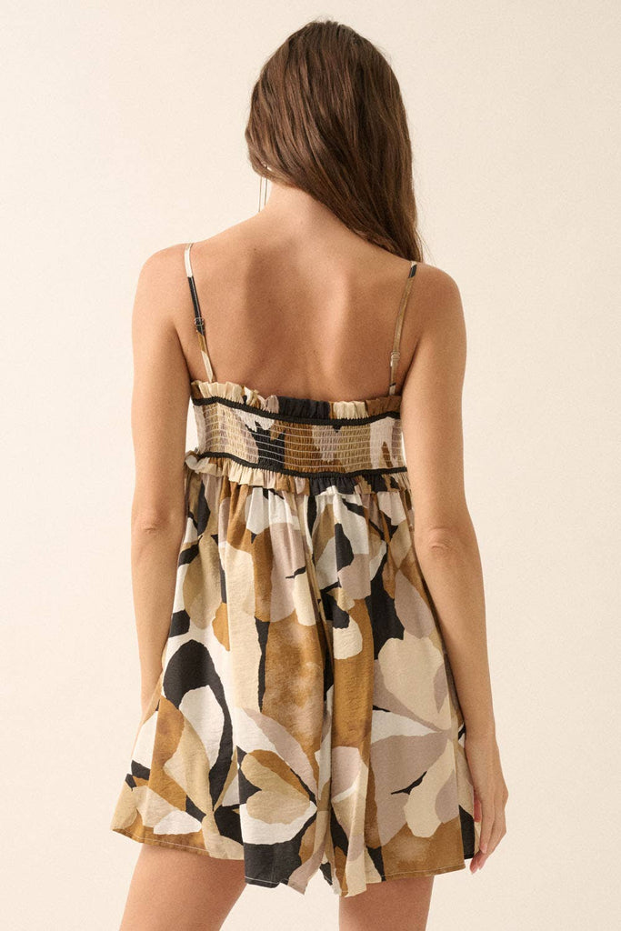 Woman wearing an abstract printed romper in warm earth tones with a smocked bodice and flowy shorts.