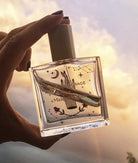 Maison Matine Avant l’Orage perfume bottle with celestial illustrations, placed among citrus fruits and sample vials on blue fabric