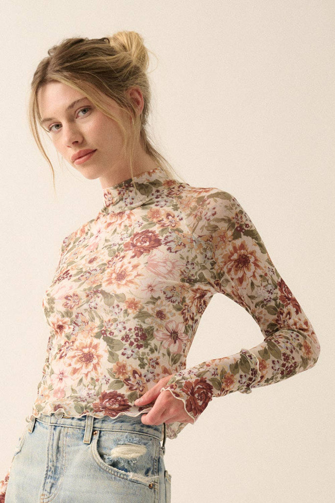 Woman wearing a sheer mesh floral long-sleeve top with mock neck and fitted silhouette.