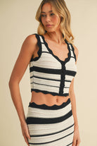 Woman wearing black and white striped crochet knit crop top and matching maxi skirt with scalloped trim