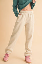 Woman wearing light heather beige fleece jogger pants with a relaxed fit and elastic waistband.