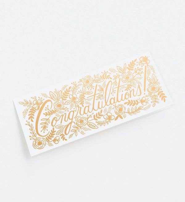 A congratulations card with intricate gold floral designs and a light blue envelope.