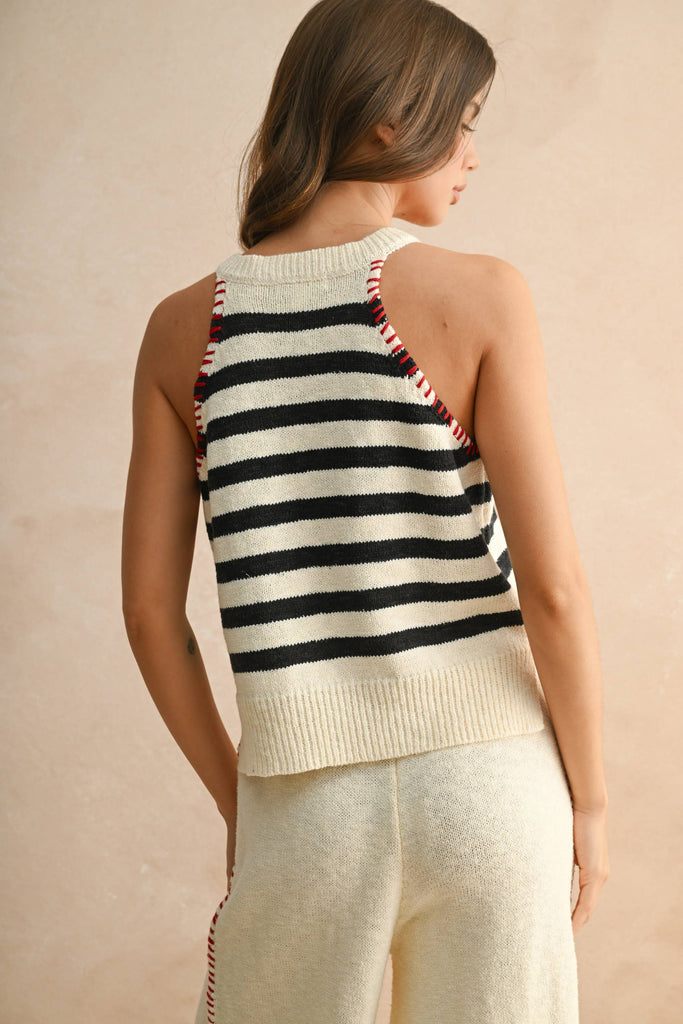 Woman wearing a cream knit set with striped sleeveless top and wide-leg pants with red drawstring.