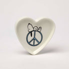 Heart-shaped trinket dish with Snoopy resting on a blue peace sign.
