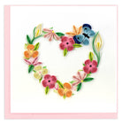 Quilled floral design in the shape of a heart on a pink background