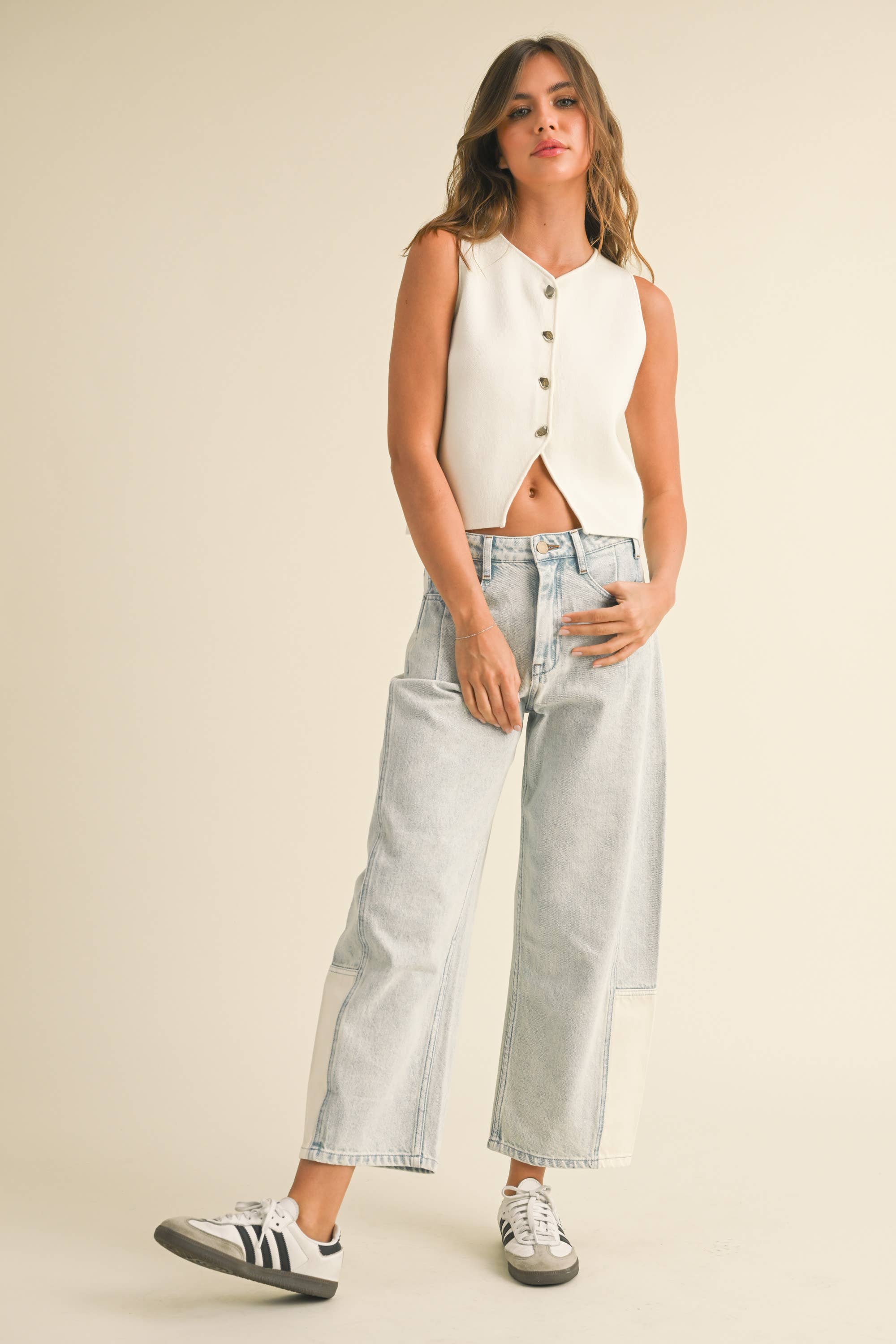 Model wearing light-wash wide-leg jeans with white contrast panels on the lower leg, styled with sneakers.