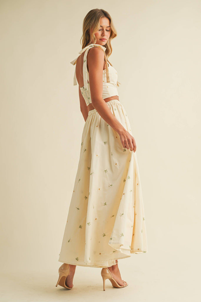 Light cream two-piece set with small floral embroidery, featuring bow-tie strap top and flowy maxi skirt