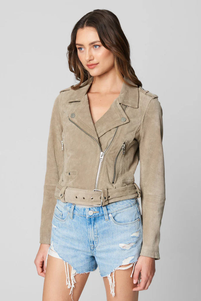 Woman wearing a beige jacket and denim shorts on a gray background