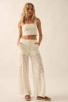 Model wearing ivory lace two-piece set with cropped top and drawstring wide-leg pants.