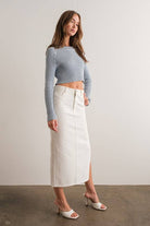 Woman wearing a light blue mock neck long sleeve rib knit cropped sweater.